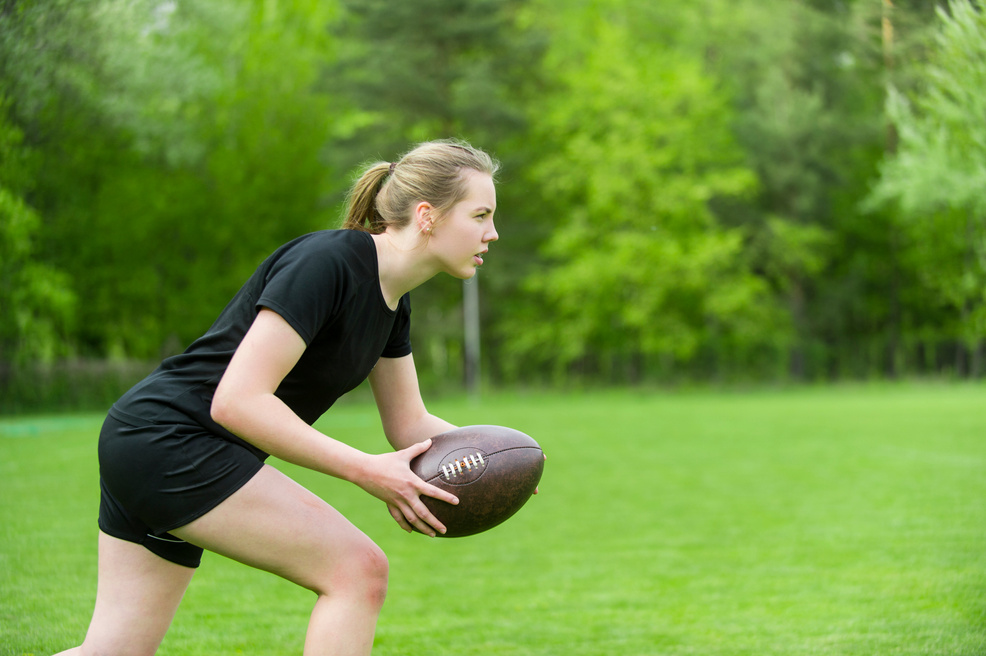 Young Woman With Rugby Ball Playing On Field
